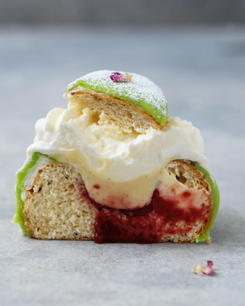 N&auml;rbild av en prinsess-semla med gr&ouml;n marsipan, fluffig gr&auml;dde, len vaniljkr&auml;m och hallonsylt.
